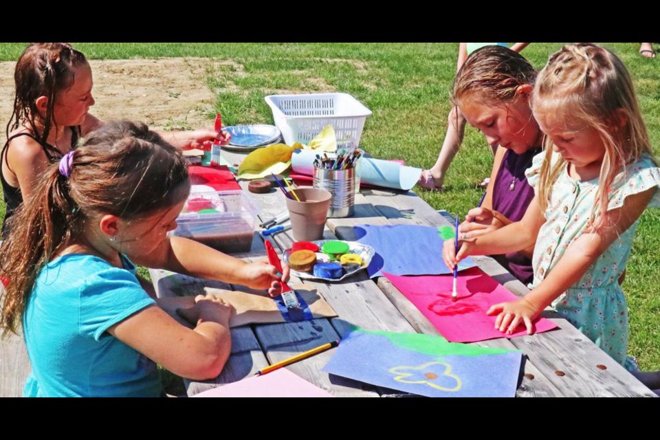 A group of girls, some still dripping from the water nozzle on the bouncy house, did some drawing at the crafts table at Nickle Lake Day.