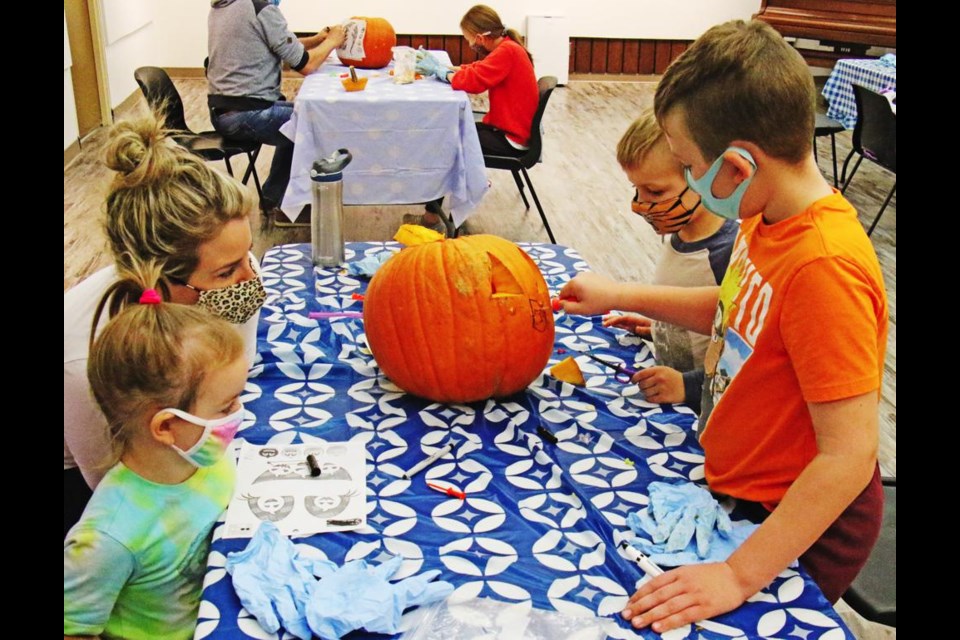 Mom Leesa and Morah Walcer watched as Weston and Keaton worked on carving a pumpkin at the Weyburn Public Library on Thursday evening.