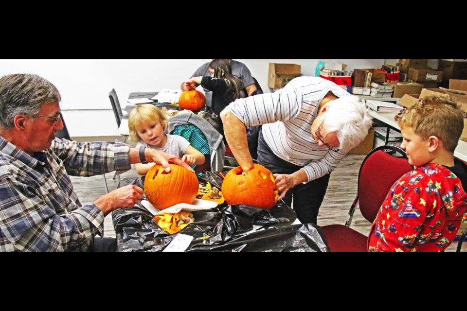 Bernard and Fran Kambeitz, and their grandsons Andy and Abby, worked together to carve a couple of pumpkins at the library on Thursday evening.