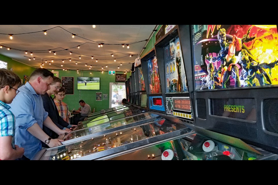 Saskatchewan Liberal Party leader Jeff Walters, second left, goes old school as he plays pinball.