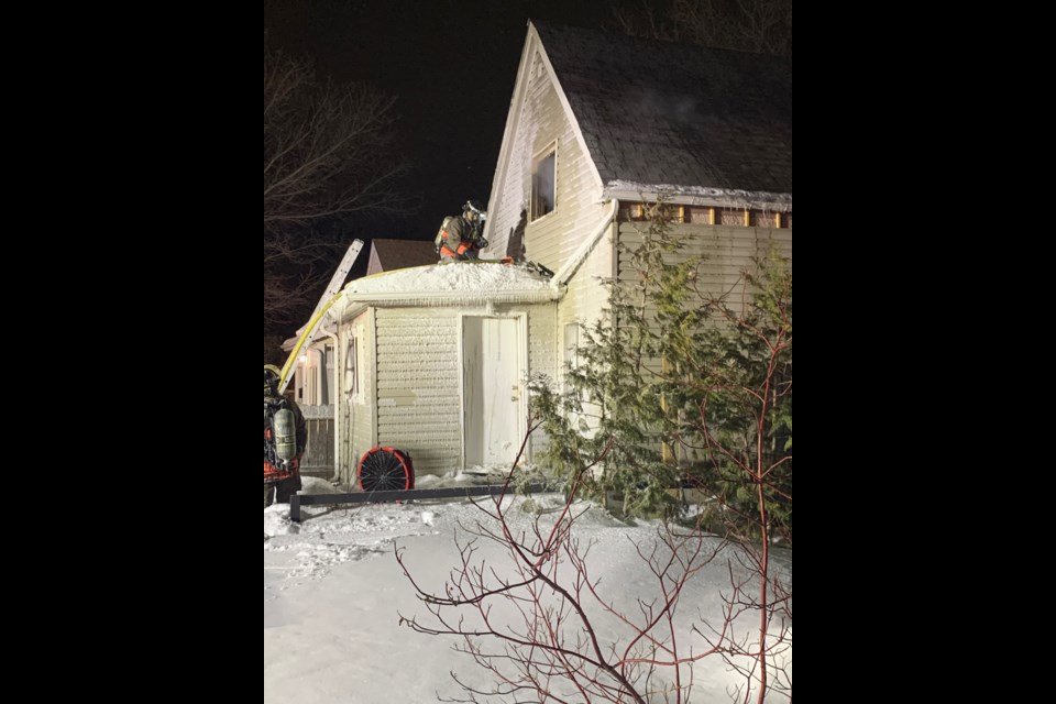 A firefighter prepares a hose line outside the second-floor window.