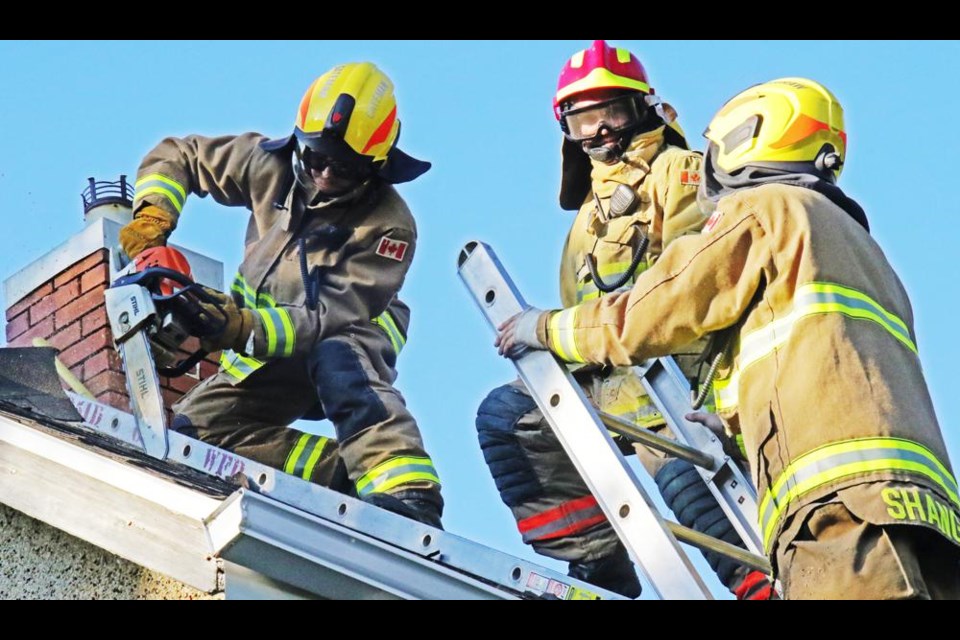 A fire fighter practices using a chainsaw to gain entry to the roof and attic area of a house, during a training exercise on Thursday evening in Weyburn.