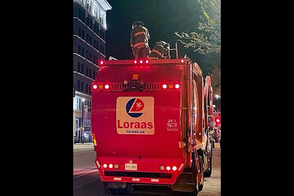 Saskatoon Fire Department crews try to locate a point of entry to determine how to safely remove the person trapped inside the garbage truck on Friday morning, Sept. 30.