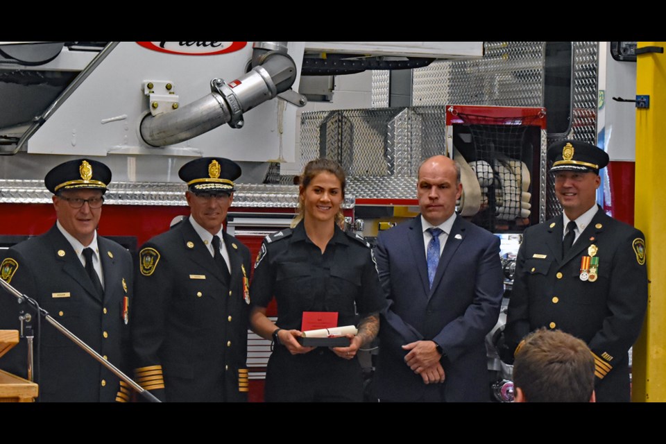 Firefighter paramedic Karla Sawatzky, center, proudly holds her badge after receiving it from Saskatoon Fire Department Chief Morgan Hackl, second left. Others in photo, from left, are SFD Deputy Chief Rob Hogan, SFD Staff Development and Safety Assistant Chief Anthony Tataryn, and International Association of Firefighters Local 80 President Morley Demarais.