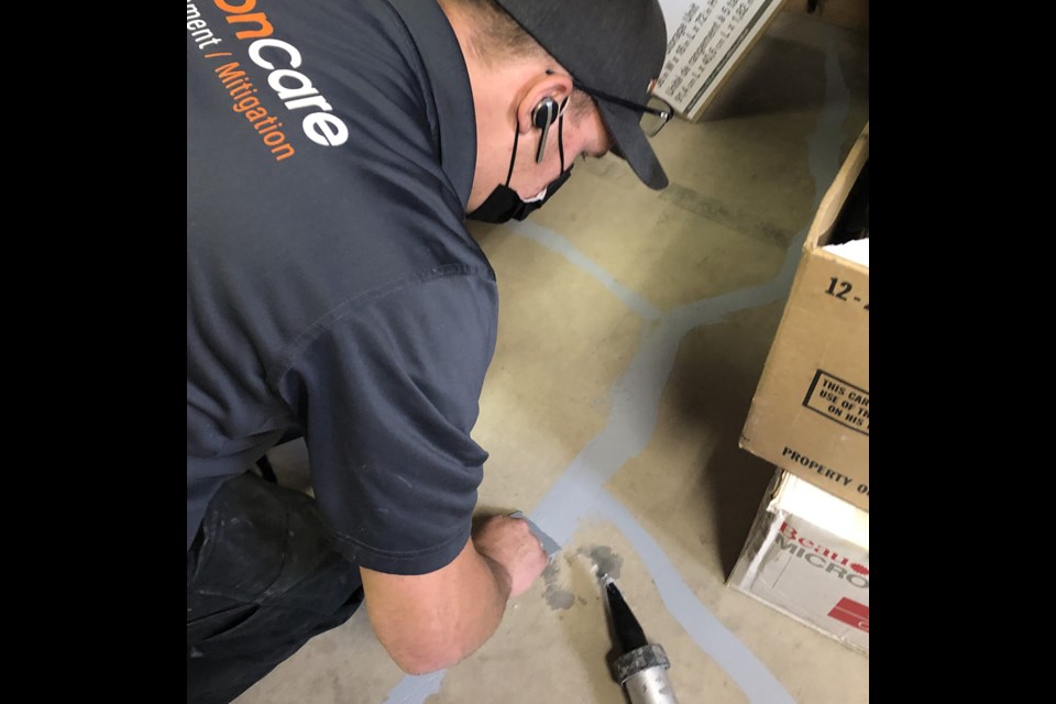 Mitigation technician seals cracks in basement floor for better suction.