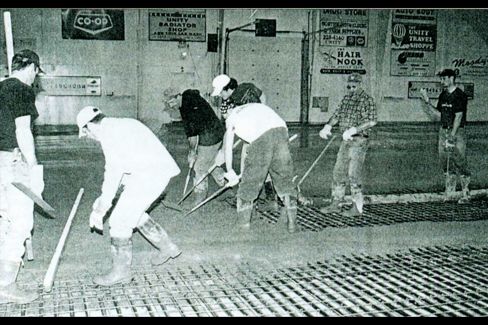 A work party helps prepare and pour a new concrete surface at the Unity curling rink, in the spring of 2002.