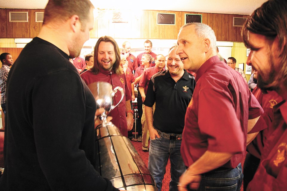 Saskatchewan Roughrider player Brendon LaBatte held the Grey Cup trophy as he met members of the Young Fellows Club on Dec. 12, 2013, including Scott Benning, Jeff Chessall and Sandy McCormick. He dropped in to visit the club at their Christmas party before heading for Radville.