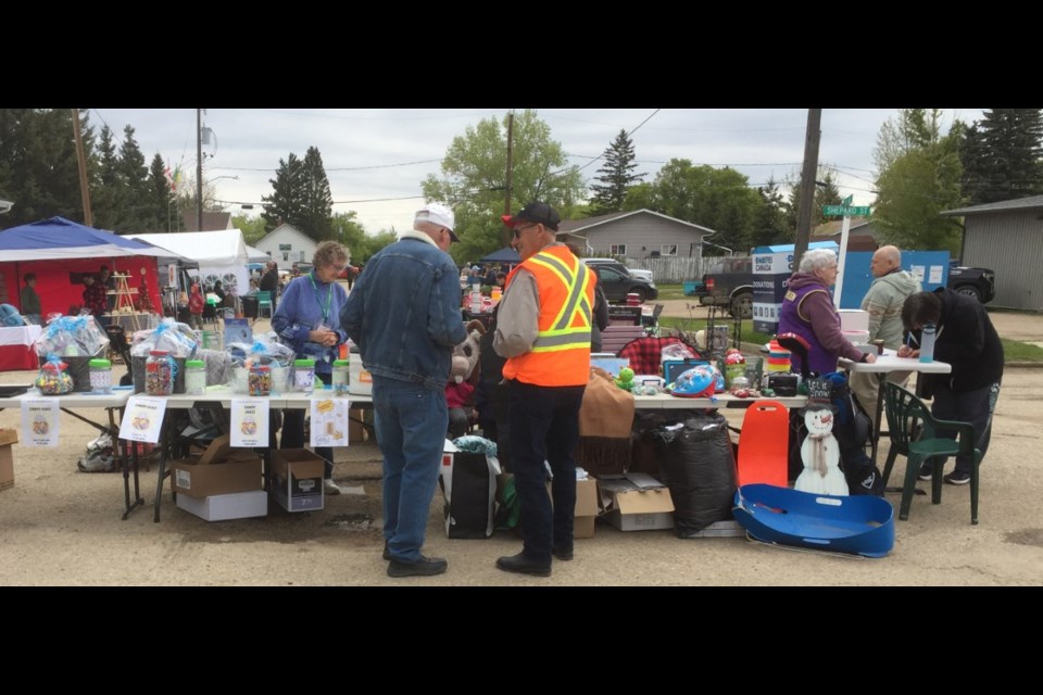 Borden Lions table at the Borden and District Lions Club outdoor flea market with Lion Bev and Lion Sandi selling and Lion Archie and Lion Ed looking everything over. 