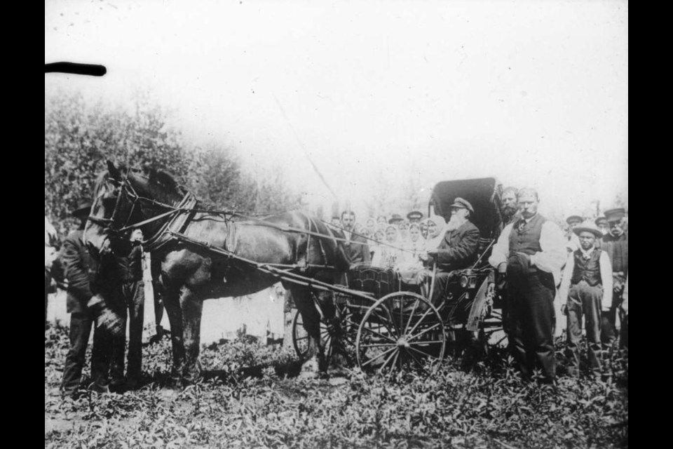 Peter V. Verigin stands behind a Roadster buggy at Otradnoye village, Sask., c. 1905. Ivan F. Makhortoff, seated, waits to pass Verigin the reigns.