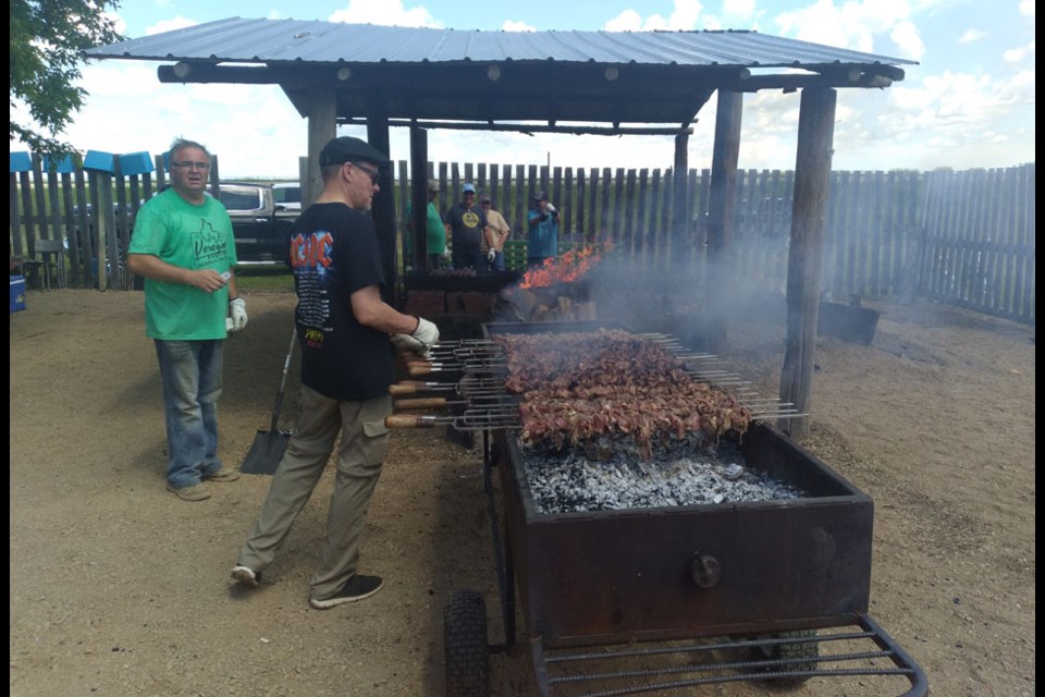 Several volunteers were needed to keep the coals hot and for turning the skewers in order to cook an appetizing course of barbecued lamb at Veregin on June 28.