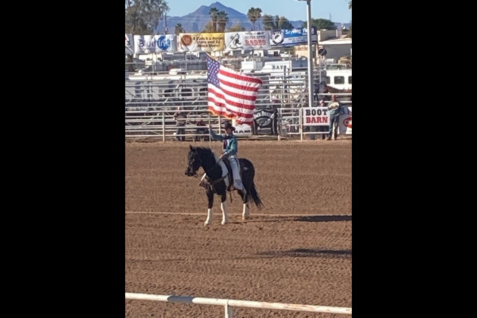 At the opening ceremony of the Yuma Silver Spurs Rodeo, a cowboy proudly carries the American flag. 