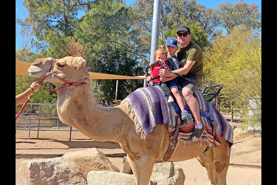 Charlotte Johnson, Shay and Ryan Woloshyn riding a camel at the Phoenix Zoo.
