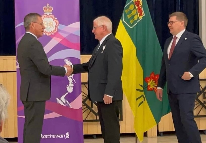 Randy Aumack being presented with a medal by Lt-Gov. Russell Mirasty with Premier Scott Moe in attendance at the Queen Elizabeth II Platinum Jubilee awards night in Shellbrook. 