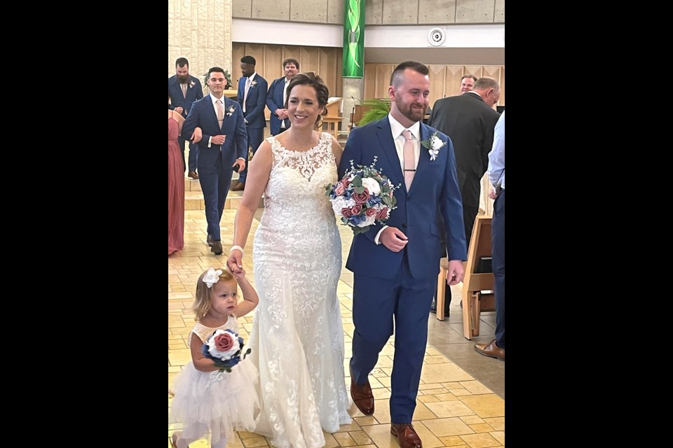 A beautiful newlywed couple, Candace and Kenzie Haubrich, and her niece as flower girl walking out after their wedding ceremony. 