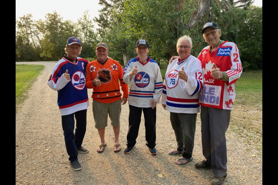 Pictured are Morris Lukowich, wearing his first jersey as Jets captain in 1980-81; Wayne Baldwin wearing the jersey worn in 1980 in Detroit when Gordie Howe played his last game and Wayne Gretzky played his first all-star game; Len Lukowich wearing 1979 jersey from the all-star game playing the Moscow Dynamo’s in Moscow; Colleen Wicks wearing the jersey of the last Jets game in WHA in 1979; and Norman Wicks wearing the jersey worn in the1994 the Spengler Cup in Davos, Switzerland.
