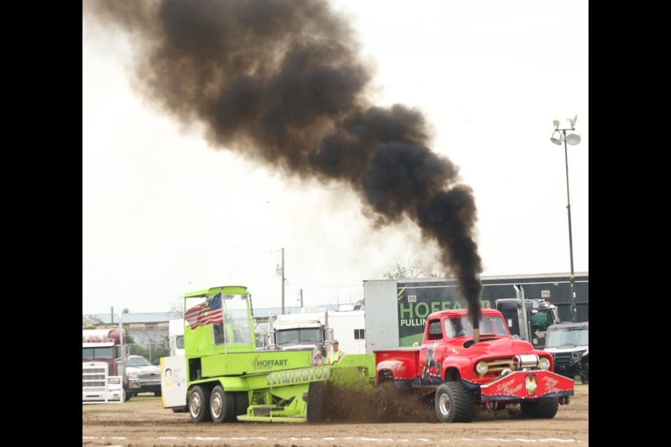 A diesel track spews smoke as it takes on the pull sled.