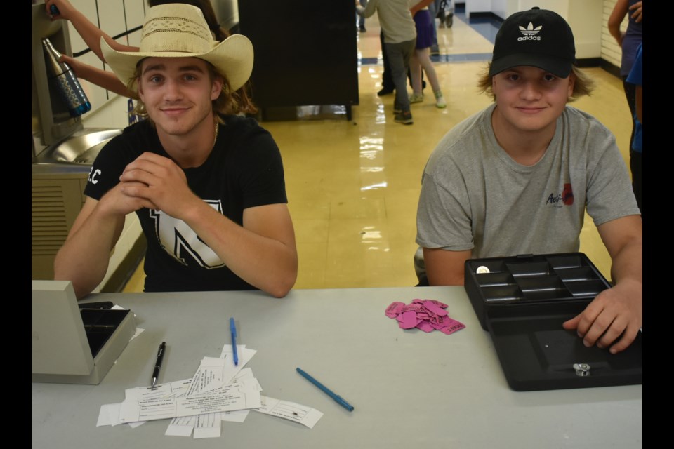 JT Foster and Keegan Dyck were two of the volunteers who sat behind one of the 50/50 raffle and burger ticket sales tables.