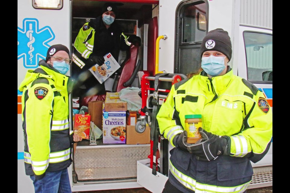 Paramedics Jessie Klatt, Stephanie Schmidt and Daniel Kelly (in back) show some of the food items they had collected by noon at the Wholesale Club on Wednesday, as part of the "Paramedics WIth Heart" foundation's food drive.