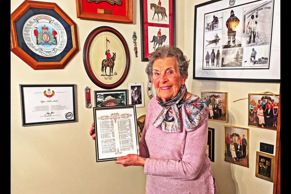 Claire Kuhn holds a copy of the page in the Book of Remembrance, which lists her father who served in the Second World War, with pictures surrounding her of the RCMP service of her late husband Ed, and son Richard.