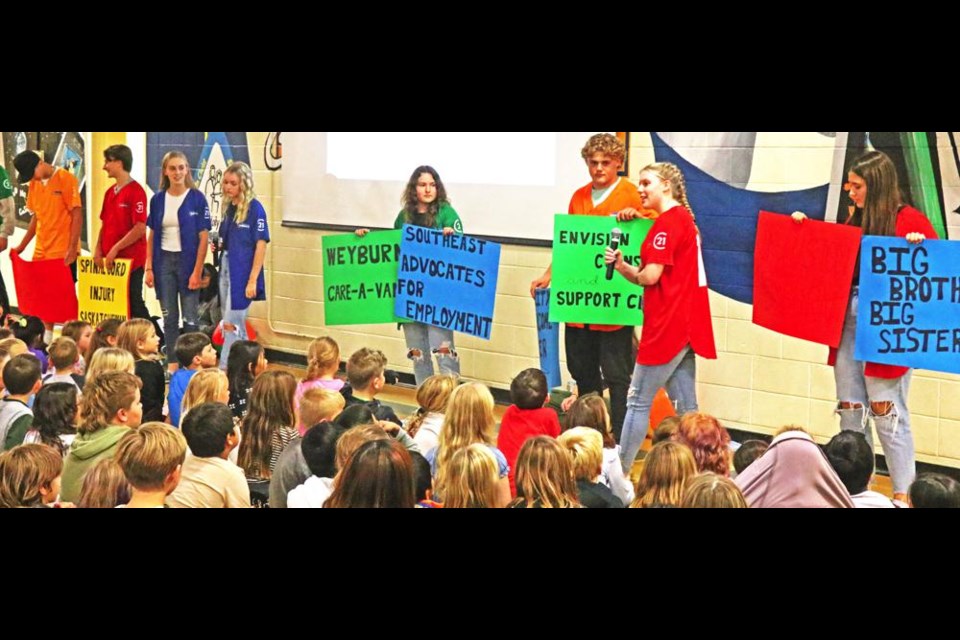 The Weyburn Communithon Ambassadors held up signs for the students of St. Michael School to see which organizations are supported by Communithon, which will be held on Friday, Oct. 27.