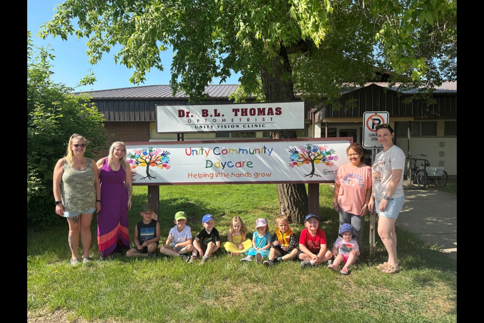 Staff and daycare children post in front of their centre, which board members are looking to upsize as the existing space is too small for their needs.