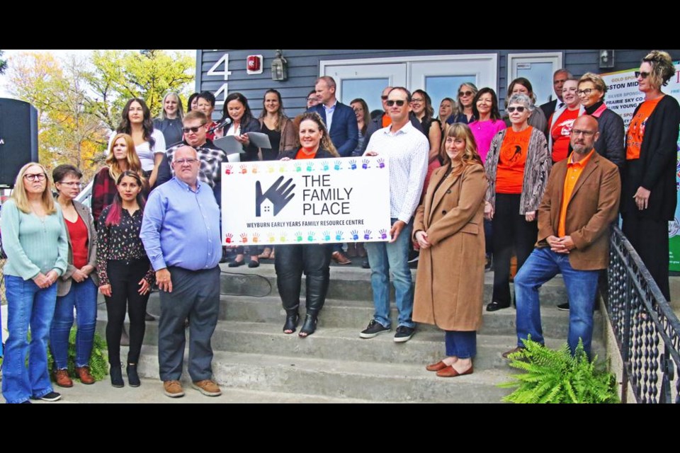 The staff of the Family Place gathered along with the board members, and Holy Family school division officials and dignitaries for a big group photo on the front steps of the Family Place's new location on Friday morning.