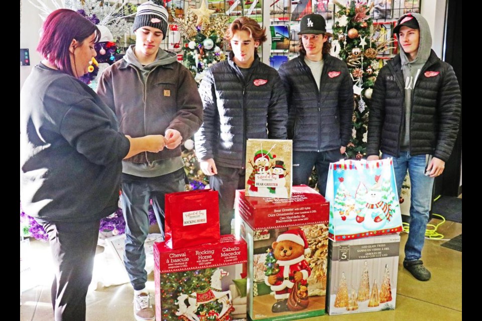 Family Place staff member Jaclyn Honeysett was handed the name of a raffle winner, as Red Wings players helped to make the draws from the Festival of Trees on Friday at E. Bourassa and Sons. The Wings included Max Monette, Lucas Schmid, Drew Molde and Wyatt LaCoste. The players helped Family Place staff to clean up after the tree festival was done, including taking trees down and delivering them to the buyers.