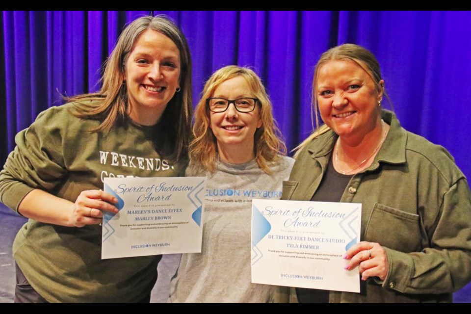 Marley Brown of Marley's Dance Effex, left, along with Tyla Rimmer of De Tricky Feet dance studio at right, accepted the Spirit of Inclusion Award from Dawn Purdue of Inclusion Weyburn on Saturday night, onstage at the Cugnet Centre. It was presented in front of a full audience, gathered for the evening performance of Inspirations of Dance.
