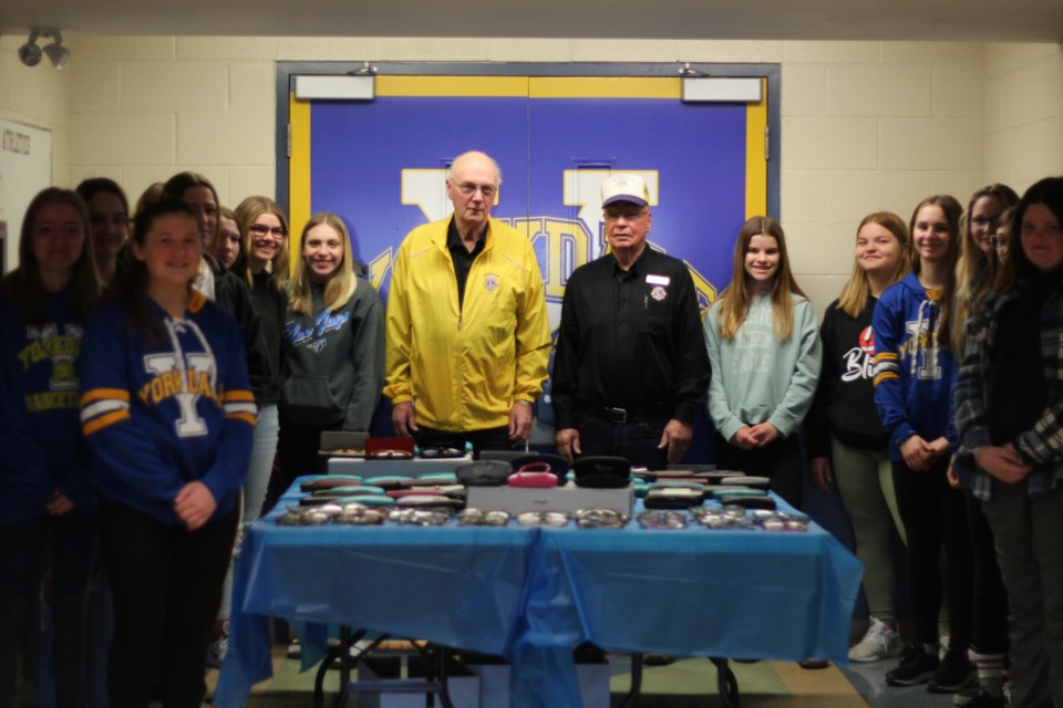 Vern Brown (left) and Allan Konkin (right) of the Yorkton Lions Club accept donated eyeglasses from students at Yorkdale Central School.