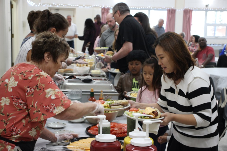 Fran Messer serves food to Sunny, and her children Ann and Jun.