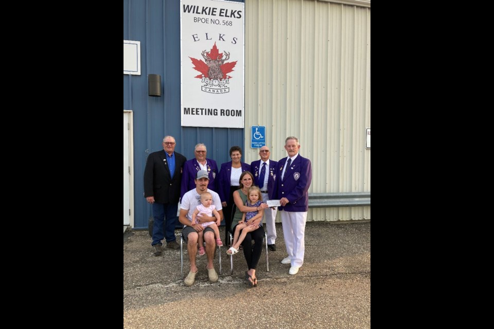 Wilkie Elks members Eugene Hartter, Daryl Glackin, Barb Glackin, Dave Glackin and Clarke Jackson make presentation to the Heather family, Catlin holding Karissa and Brittany holding Kinsley.