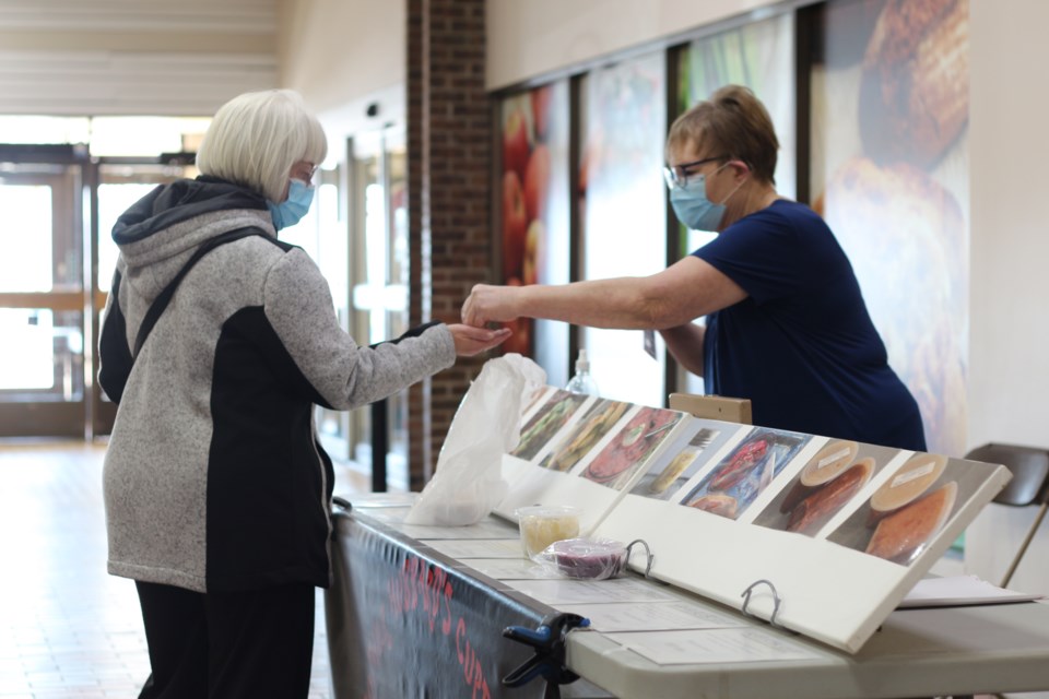 A vendor exchanges goods with a customer at the Yorkton Farmers Market.