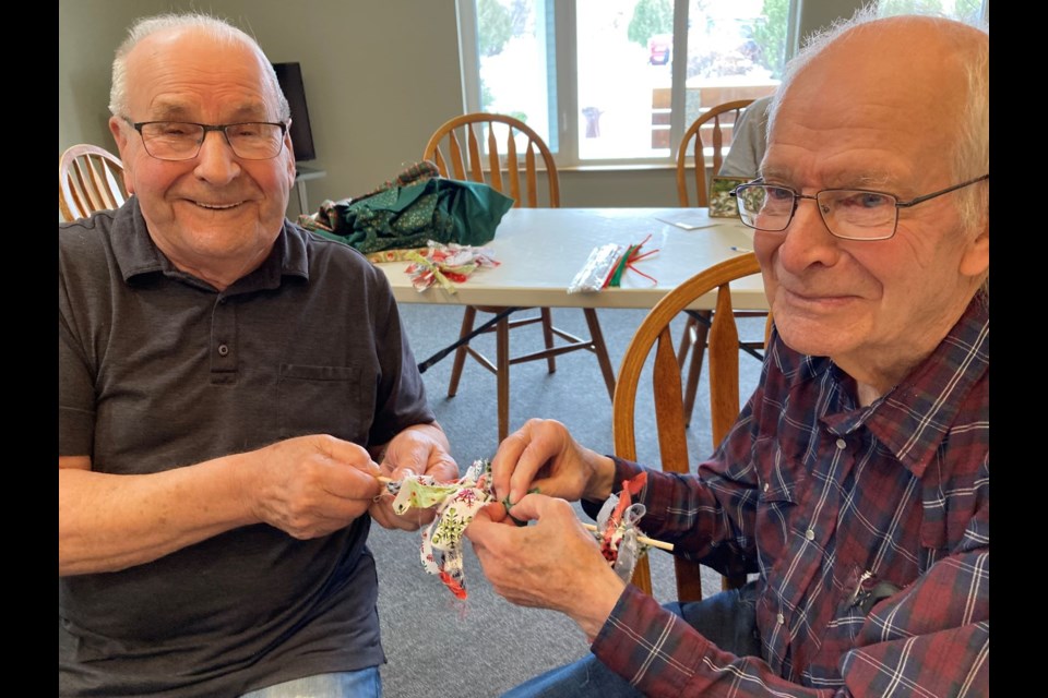 Parkview Place residents Jerome Boser and Bill Meek work as a team completing creations to be mailed out in the spirit of Christmas.