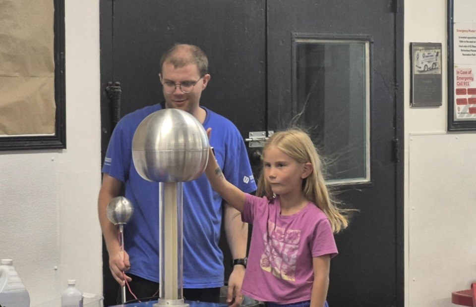 Go! Science host, Ben, allows one of the participants to touch the Van de Graaff generator, which sends her hair in different directions.