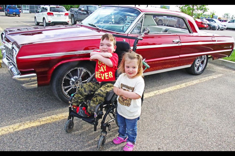 Isaiah Evans and his little sister Gracie posed in front of Isaiah's favourite car at the car show, held for the Family Day fundraiser on Sunday to help his family be able to buy a medical van to safely transport him.
