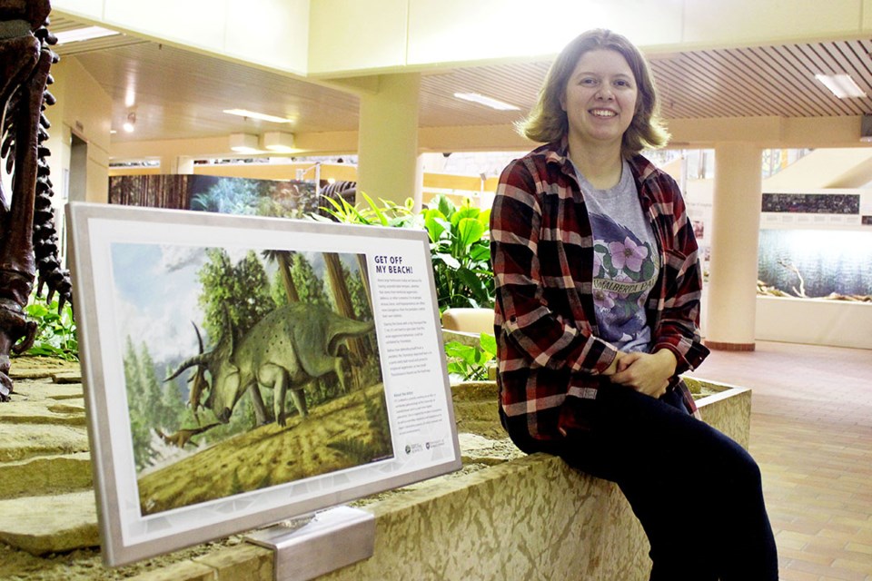 USask student Kaitlin “KT” Lindblad sits next to her paleoartistic rendition of the Triceratops in the Geology Building.  
