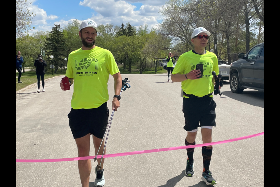 David Morin on the left, and Mike  Hanson on the right, cross the finish line after completing an over 40K run in Regina Friday.