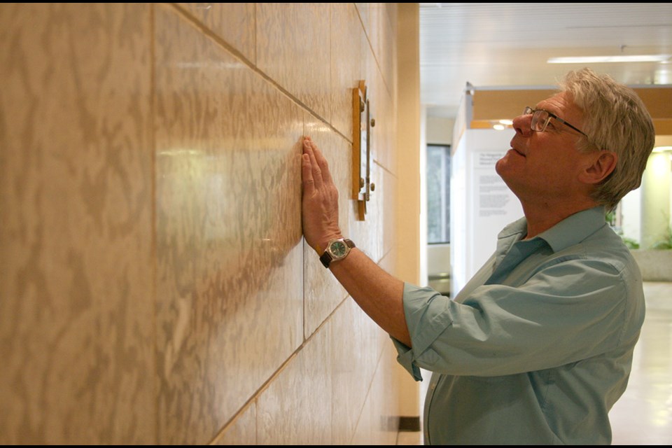 USask paleontologist Brian Pratt examines the fossils embedded in Tyndall Stone that makes up the Memorial Wall located in the Geology Building.  