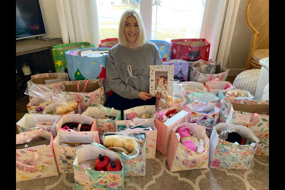 Amy Briggs sits amongst a number of packages to be delivered to breast cancer warriors, as a pay-it-forward in memory of her mom, Vicky Rissling.