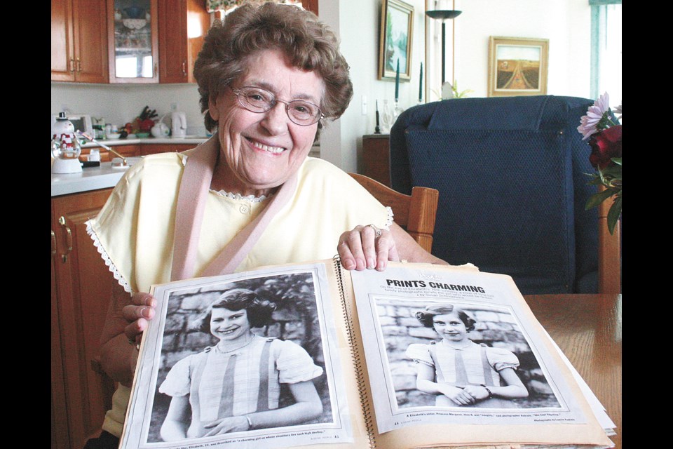 Kathryn Groshong holds up her scrapbook of royal pictures, newspaper clippings, and mementos. She has been keeping a scrapbook of the British Royal Family and collecting royal souvenirs since she was 13 years old. Her hobby began in 1939 when she went to see King George VI and Queen Elizabeth visit Regina and her mother encouraged her to start a royal scrapbook. 