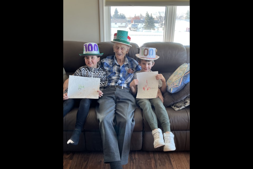 Great-grandchildren Eleanor Anderson and Clark Anderson happily pose with Grandpa Lorne Swarbrick and the pictures they made for him at Grandpa’s 100th birthday party, Feb. 11. As Swarbrick’s actual birthday wasn’t until Feb. 12, he insisted on having only “99” on his party hat.