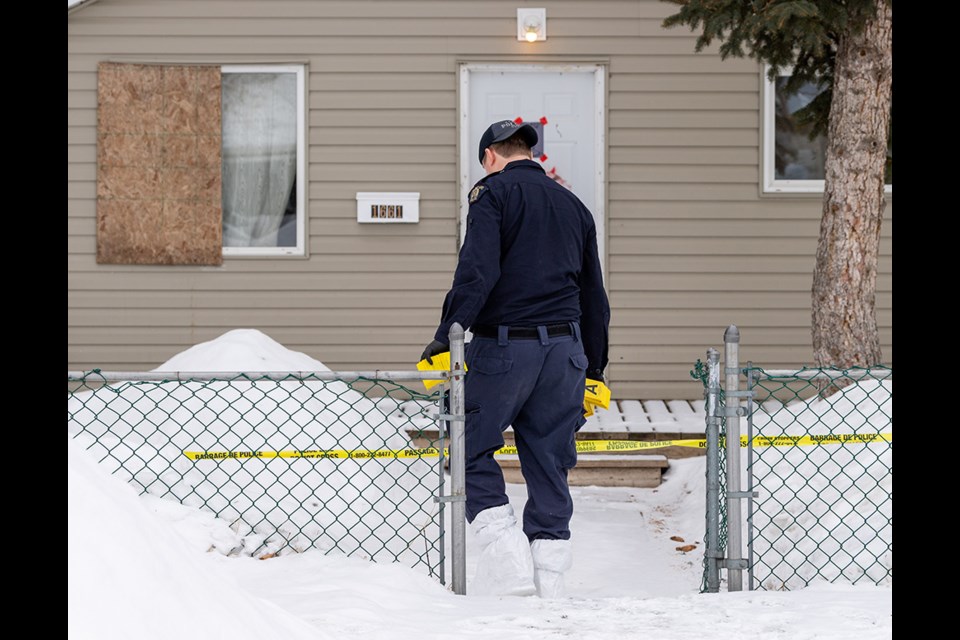 A forensics officer carries markers to a house as part of an investigation at 1661-102nd Street in North Battleford. 