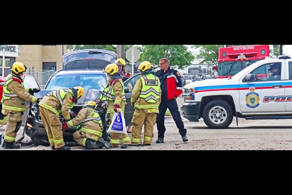 Fire fighters make sure there are no hazardous leaks from the front of this SUV, which collided with a SaskTel truck on Tuesday in Weyburn.