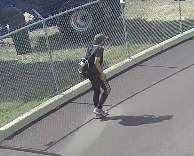 Suspect was observed wearing a green ball cap, black shirt, black pants with a white stripe, gray shoes and a black backpack with white accents.