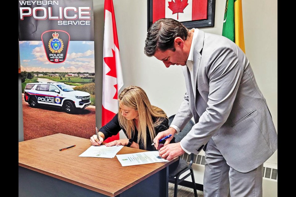 Nicole Robinson signs as city solicitor Mike Weger watches, after administering the oath as Weyburn's newest constable on Monday.