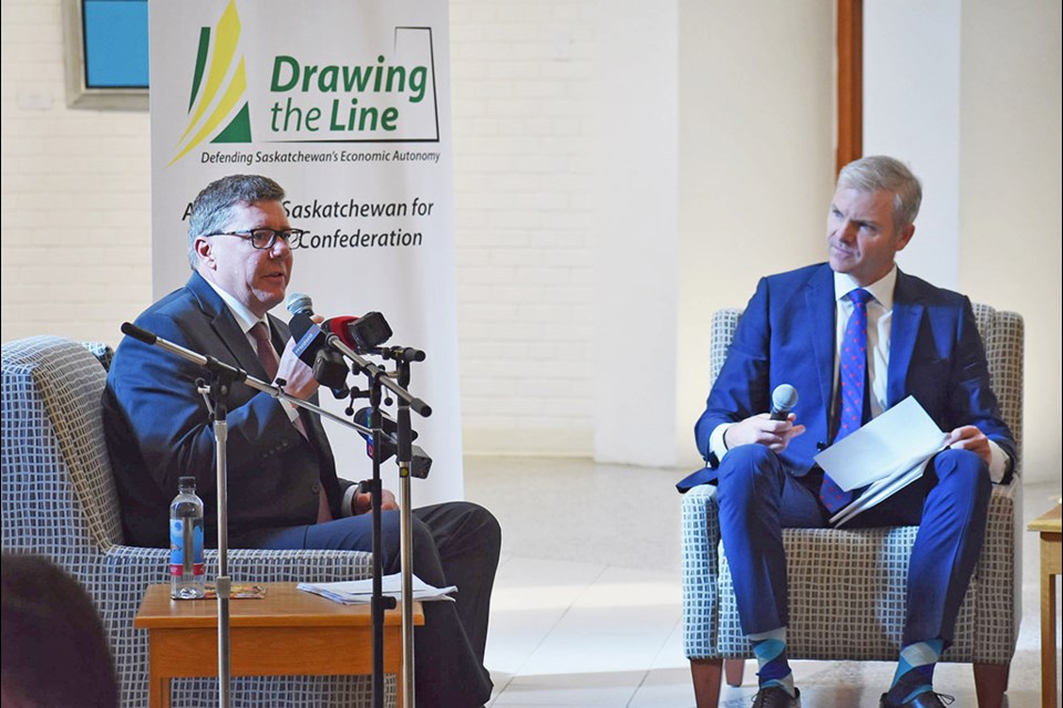 Premier Scott Moe, pictured with Tim MacMillan, speaks at the Chapel Gallery on Tuesday as he outlines the Sask. government's plans to Draw the Line with Ottawa over provincial resource authority.