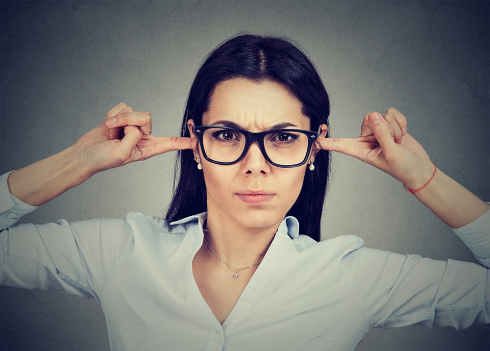 Angry woman plugging her ears with fingers