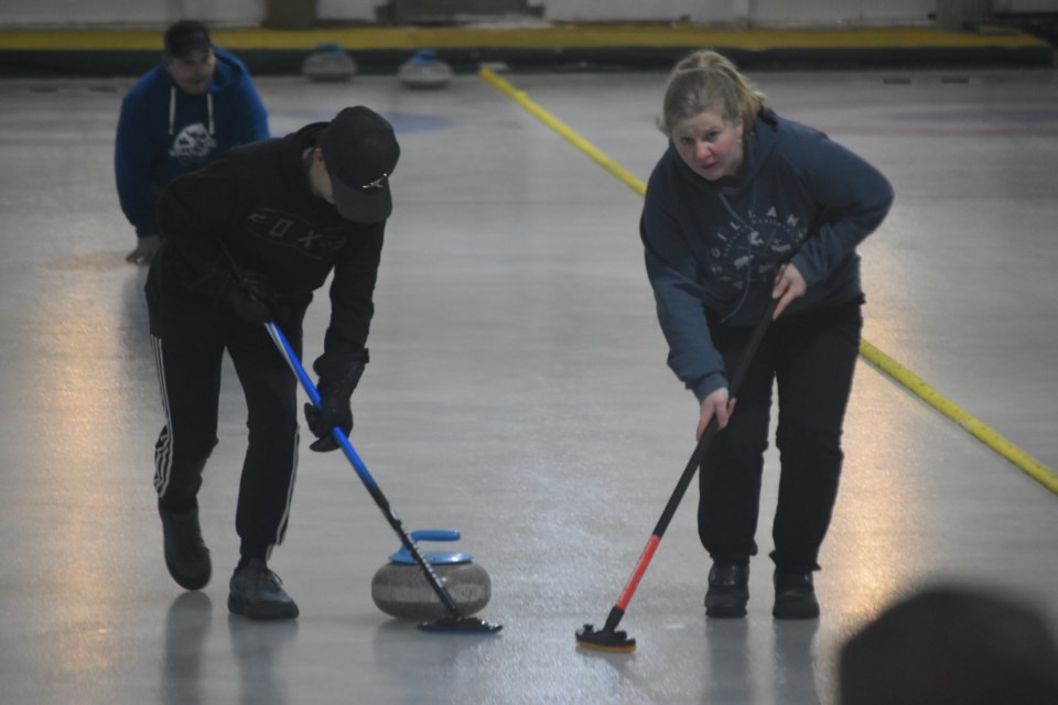 Darwin Homeniuk threw the rock while, Kayden Homeniuk, left,  and Jennifer Homeniuk swept.