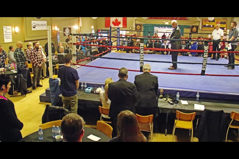 The audience in the Weyburn Legion Hall stood and held a moment of silence for the late Hank Hartenberger, in honour of his legacy for boxing in Weyburn, led by Mayor Marcel Roy, centre, in the ring.