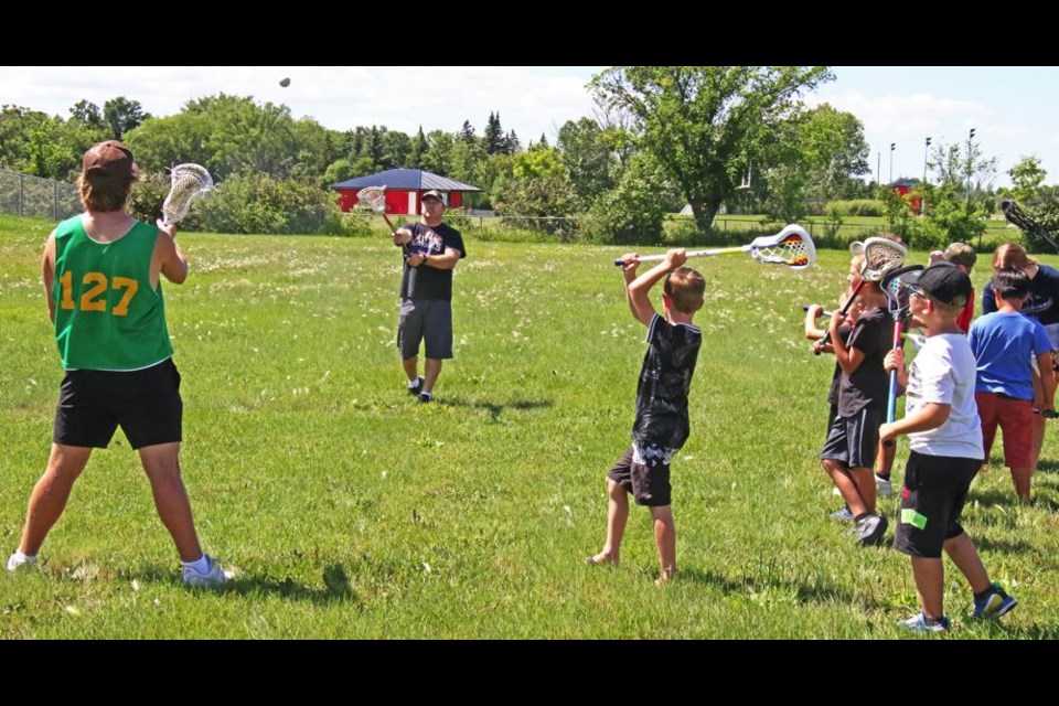 Lacrosse coach Charles Hignett demonstrated proper passing technique in an introduction to field lacrosse to children in the College for Kids program on Thursday.